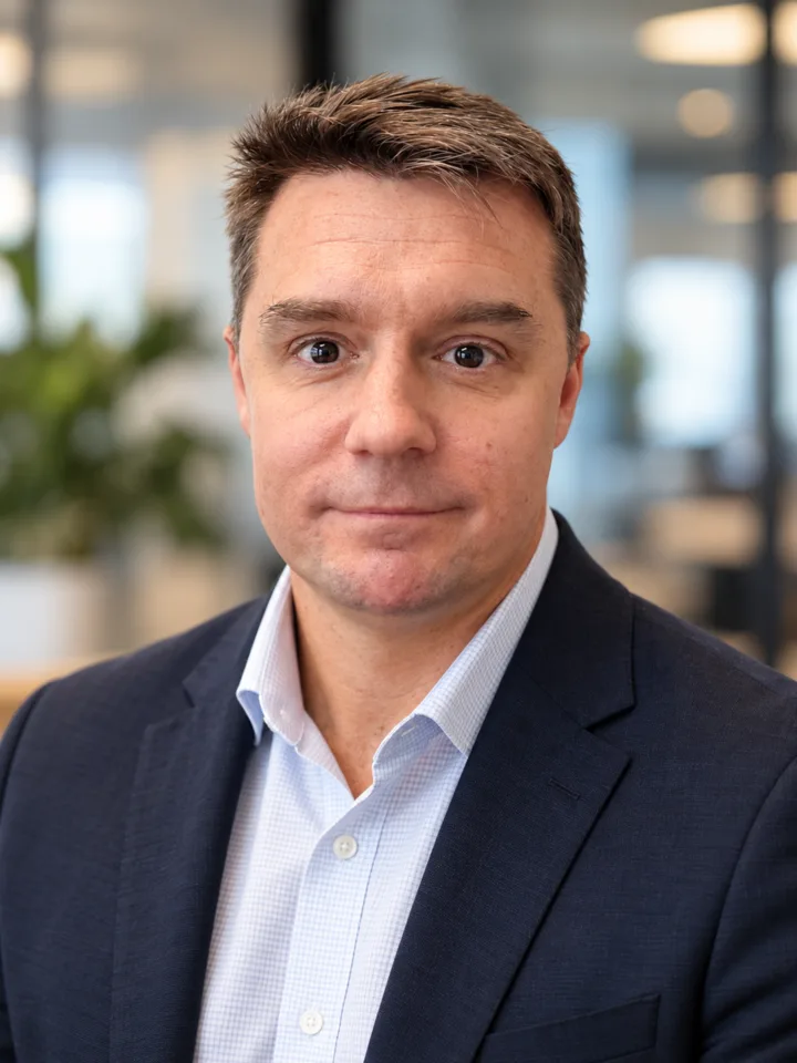 Ben Harris, founder of November One, in a navy blazer in a bright office.